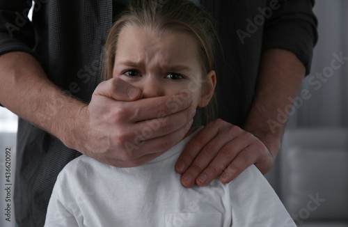 Man covering scared little girl's mouth indoors. Domestic violence © New Africa