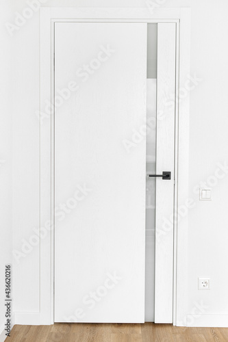 Full lengh photo of modern white door with anthracite door handle. Scandinavian style.