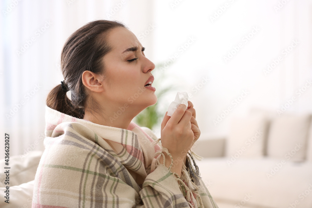 Young woman suffering from runny nose in living room Young woman suffering from runny nose in living room