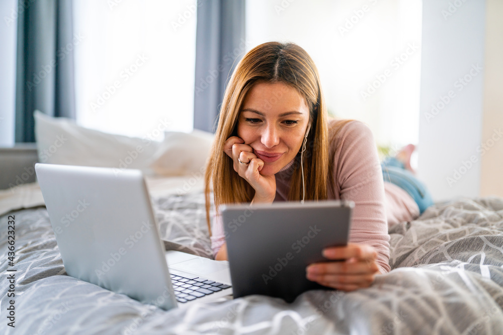 Happy woman working, surfing with laptop on the bed at home Happy woman working, surfing with laptop on the bed at home