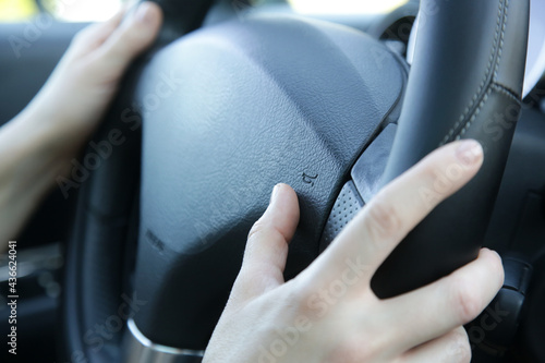 Woman hands on steering wheel pressing a horn photo