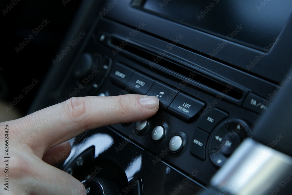 Woman set up music in car. Car dashboard close up Woman set up music in car. Car dashboard close up