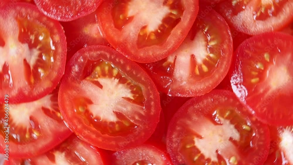 Juicy ripe red tomato is sliced rotates in a circle. cooking of a healthy diet dish from vegetables. Juicy ripe red tomato is sliced rotates in a circle. cooking of a healthy diet dish from vegetables.