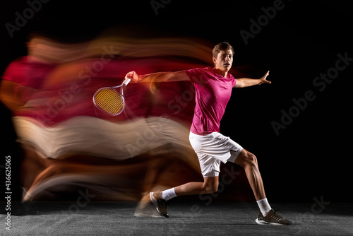 One man, male tennis player training isolated in mixed neon light on dark background. Concept of sport, team competition.