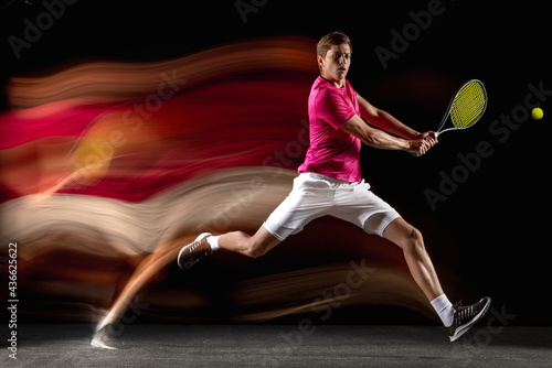 One man, male tennis player training isolated in mixed neon light on dark background. Concept of sport, team competition.