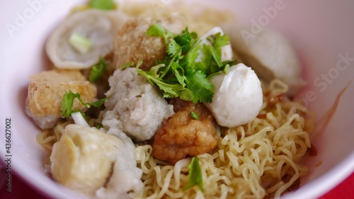 Selective focused dried egg noodle with fish ball and shrimp ball in bowl, street food in Thailand.