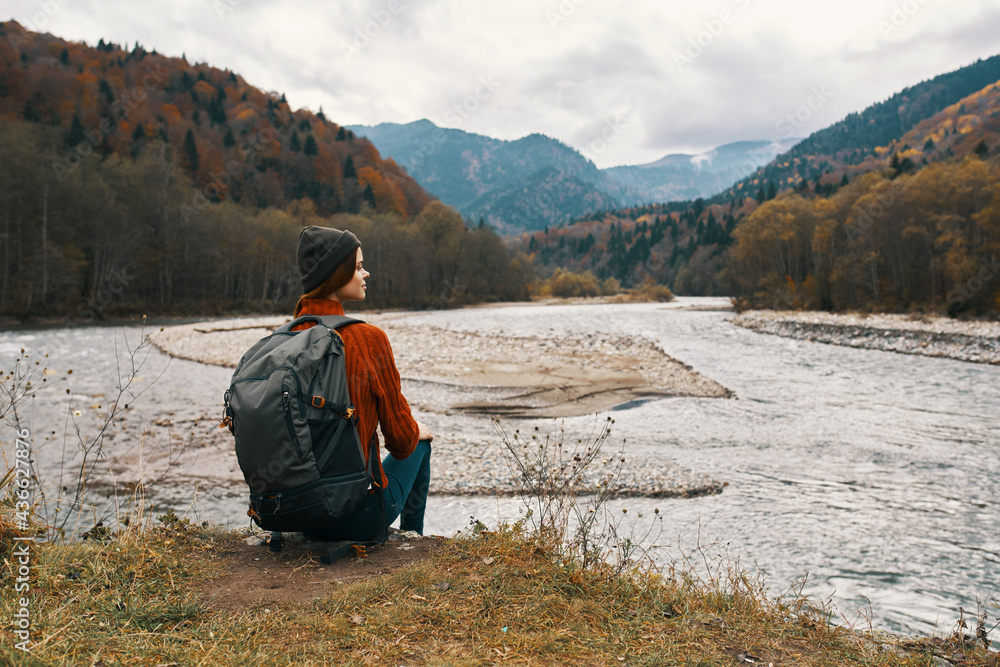woman travels in the mountains near the river in nature and looks at the mountains in the distance woman travels in the mountains near the river in nature and looks at the mountains in the distance