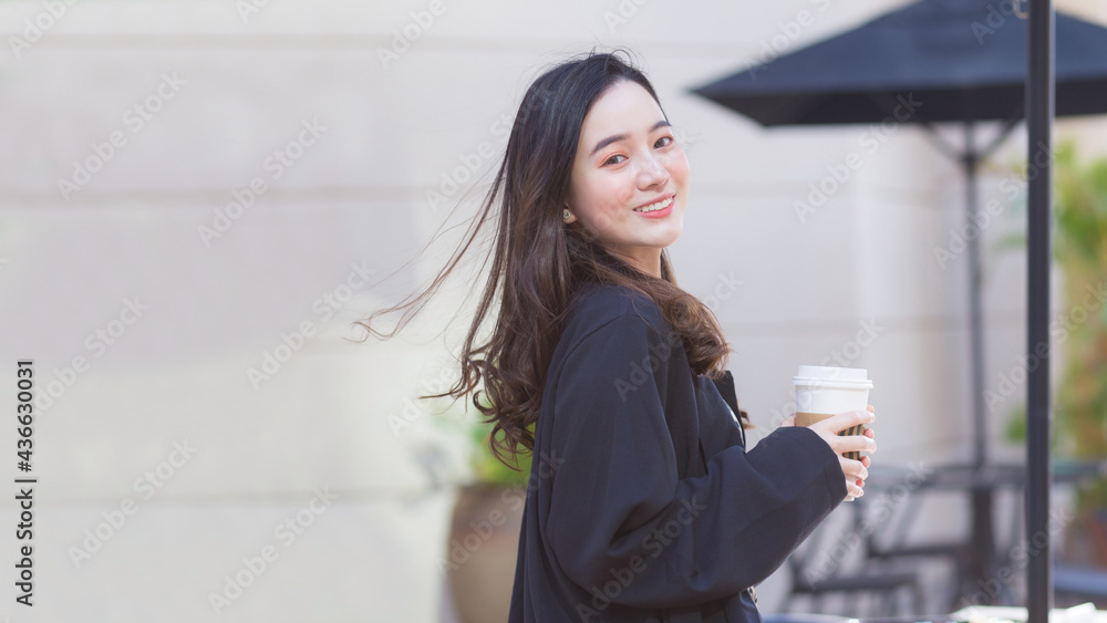 Asian beautiful woman in a dark blue suit is stand smile happy. In front of the coffee shop in the sunny morning Asian beautiful woman in a dark blue suit is stand smile happy. In front of the coffee shop in the sunny morning