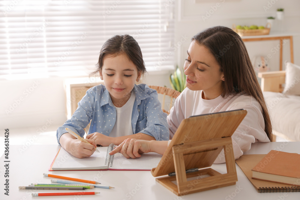Mother helping her daughter with homework using tablet at home Mother helping her daughter with homework using tablet at home