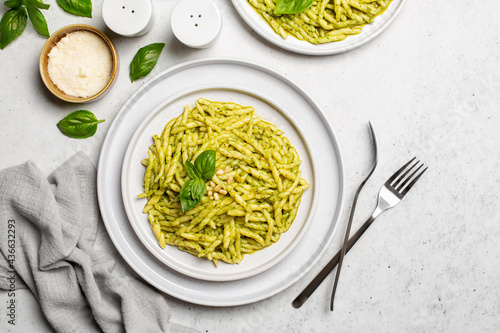 Italian dish - Trofie al pesto, pasta with pesto sauce made from basil leaves, hard cheese, pine nuts, garlic, olive oil.  Light background, top view.