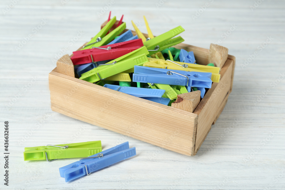 Crate with colorful clothespins on white wooden table Crate with colorful clothespins on white wooden table