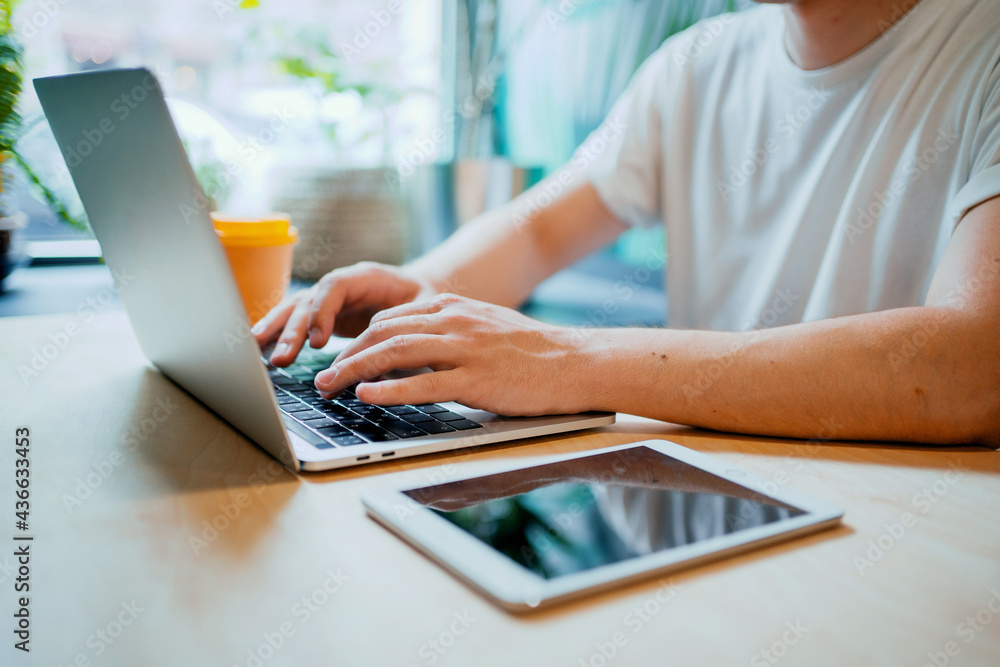 Naklejka premium the programmer works in a cafe on a laptop. Remote work manager in a restaurant with a computer. Modern device order online on the website.