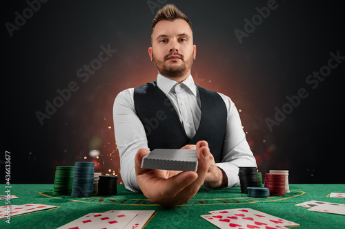 Male dealer at the casino at the table. Casino concept, gambling, poker, chips on the green casino table. photo