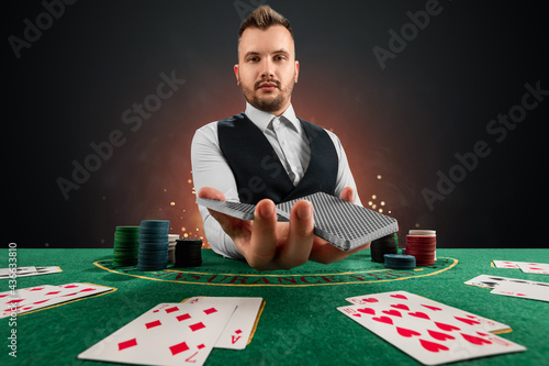 Male dealer at the casino at the table. Casino concept, gambling, poker, chips on the green casino table.