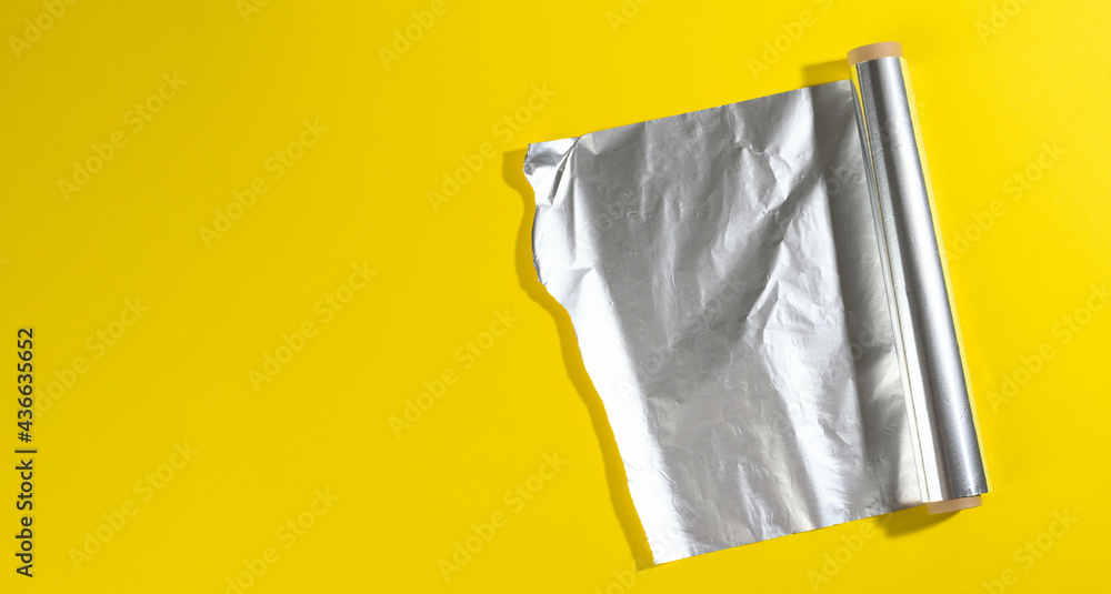 roll of twisted food foil for packaging food on yellow background roll of twisted food foil for packaging food on yellow background