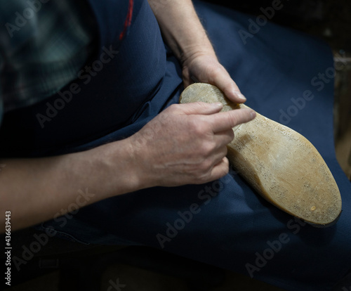 a shoe last in the hands of an elderly man. Shoemaking, tradition, renovation, journeyman, private business. Secrets of quality footwear, skillful hands of a professional