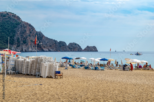 Alanya, Turkey - October 23, 2020: Damlatas beach in Alanya. A pile of plastic sun loungers against the backdrop of a beautiful seascape with rocks in the sea photo