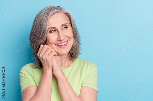 Photo of attractive dreamy old woman hold fists face good mood look empty space isolated on pastel blue color background