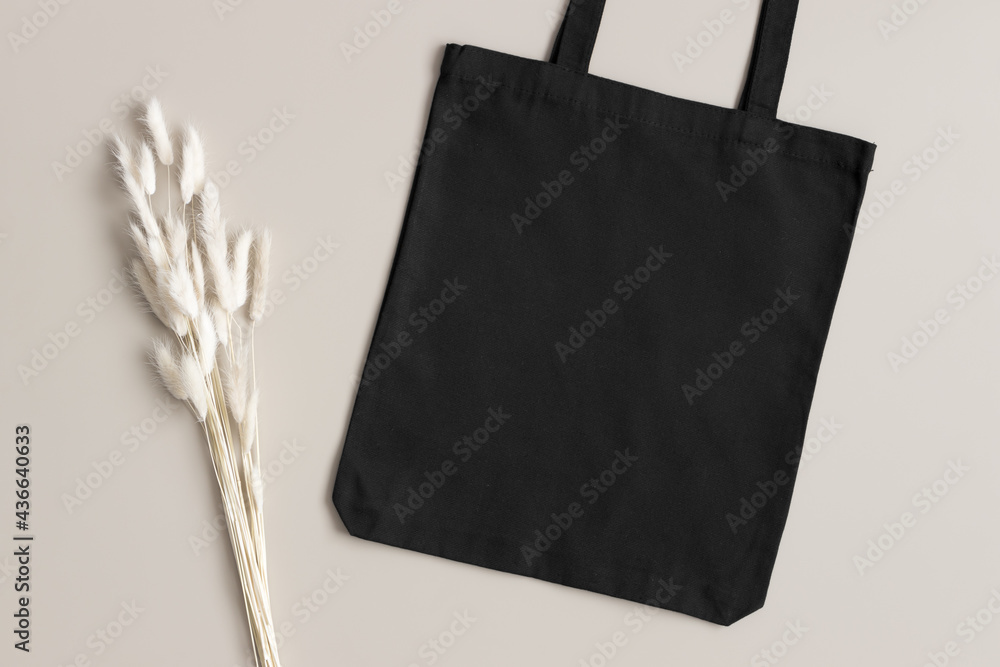 Black tote bag mockup with a lagurus decoration on the beige background ...