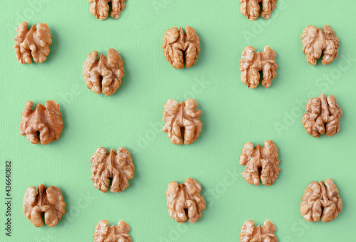 Halves of walnuts on a green trendy color 2021 year background, pattern, flat lay.