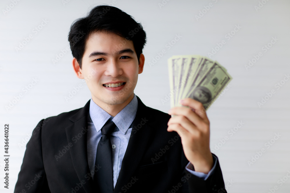 Selective focus on Asuab businessman holding dollar bank notes or money with blur foreground. Financial Concept. Selective focus on Asuab businessman holding dollar bank notes or money with blur foreground. Financial Concept.