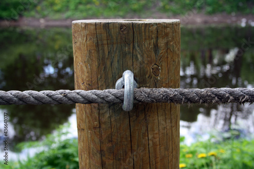 Fastening the rope to a round log. Fence made of logs and rope. © Ольга Яковлева