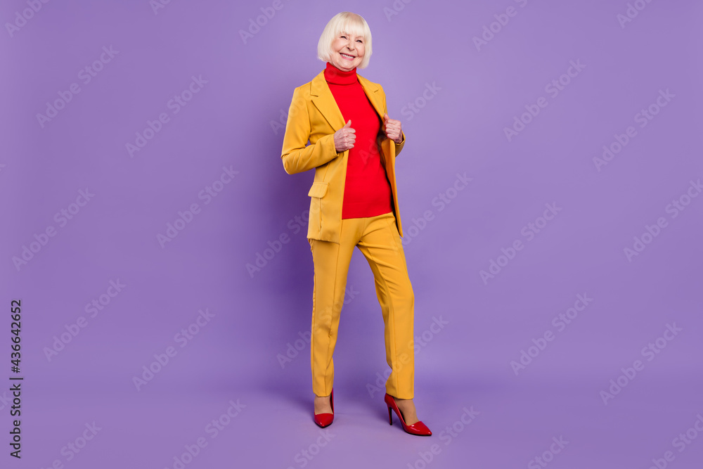 Full length photo of positive cute short hairdo aged lady wear yellow suit isolated on purple color background