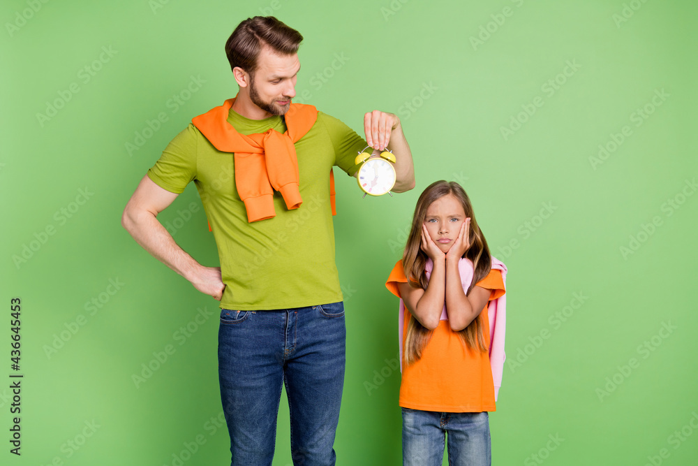 Obraz premium Portrait of nice upset people dad holding clock girl waking up early morning punctuality isolated over green color background