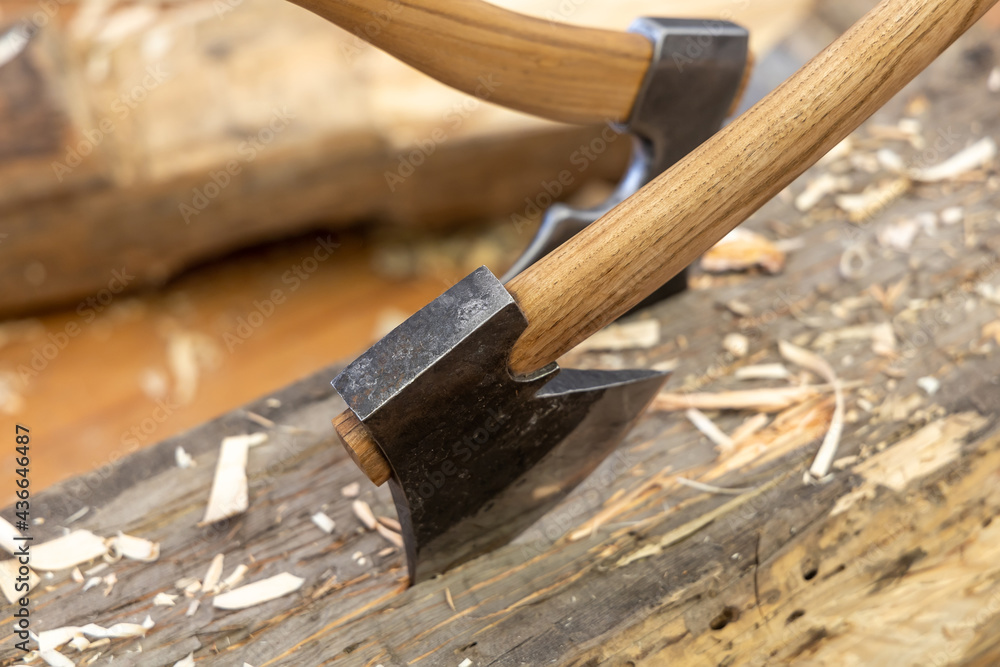 Carpentry concept. The axes are driven into a wooden log. Works in a carpentry workshop