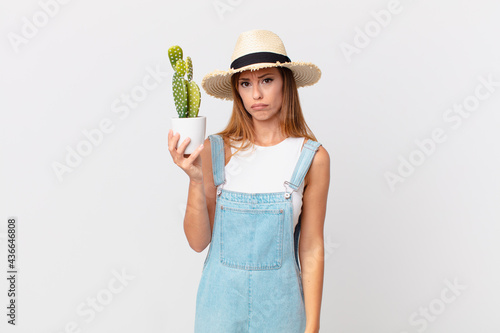 pretty woman feeling sad and whiney with an unhappy look and crying and holding a cactus decorative plant photo