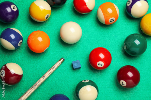 Photography Set of billiard balls with cue and chalk on green table, flat lay