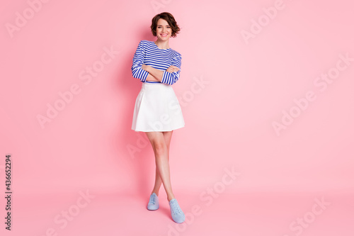 Full length photo of pretty girl crossed hands wear striped shirt short skirt footwear isolated pastel pink color background photo