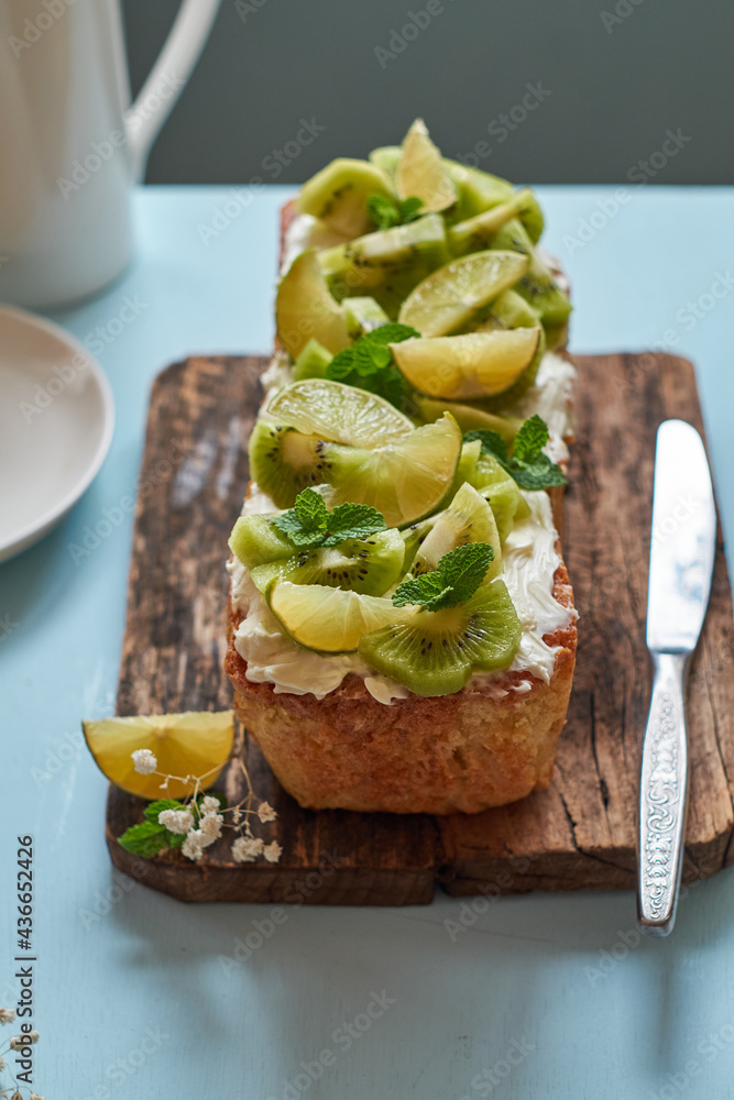Citrus bread garnished with kiwi and lime. Blue background, side view.
