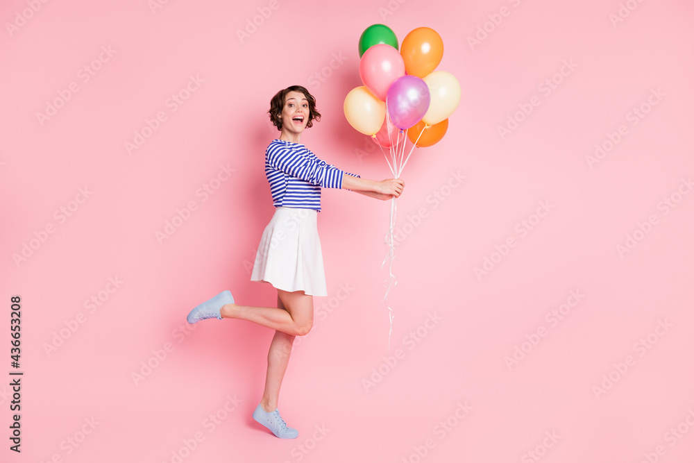 Full size profile side photo of young beautiful cheerful excited girl hold balloons present isolated on pink color background Full size profile side photo of young beautiful cheerful excited girl hold balloons present isolated on pink color background