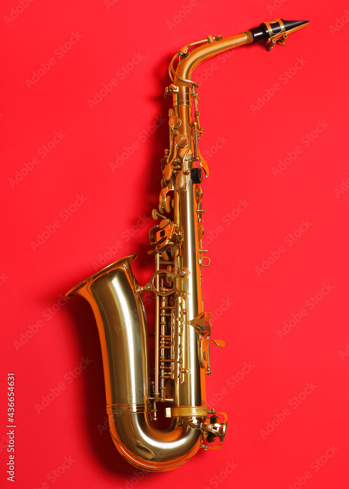 Fototapeta premium Beautiful saxophone on red background, top view