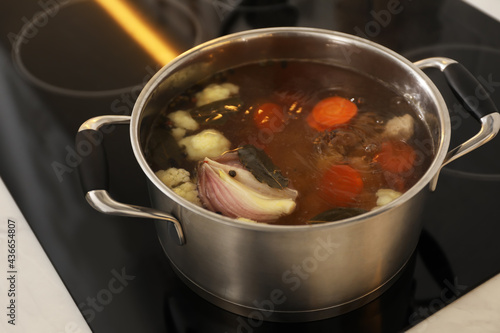 Pot with delicious bouillon on stove, closeup. Homemade recipe
