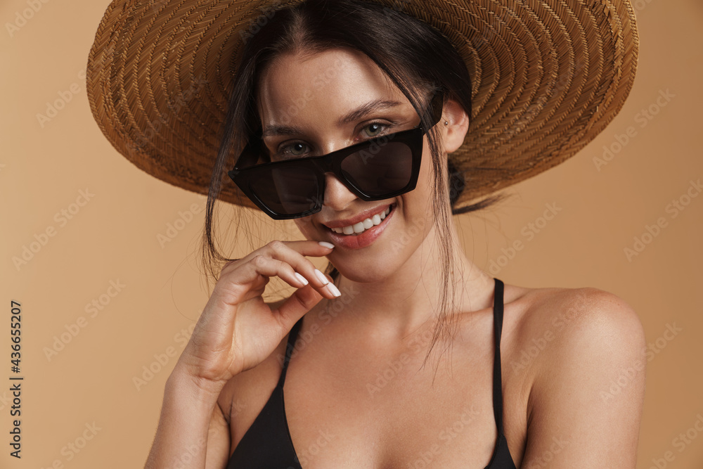Young brunette woman in straw hat smiling and looking at camera