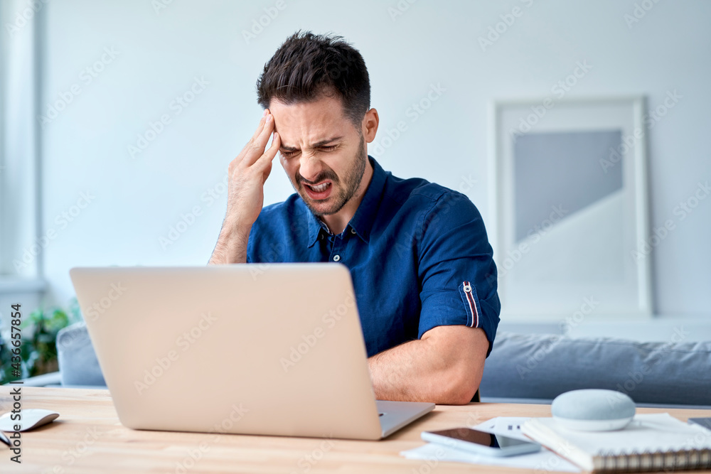 Man having headache migraine while working at home office Man having headache migraine while working at home office