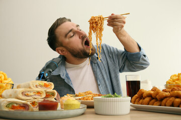 Food blogger eating in front of microphone at table against light background. Mukbang vlog
