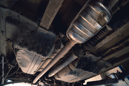Vehicle underbody exhaust pipe, catalyst, resonator, exhaust system. Old parts require repair and replacement. Car service and maintenance. cardan and outboard bearing