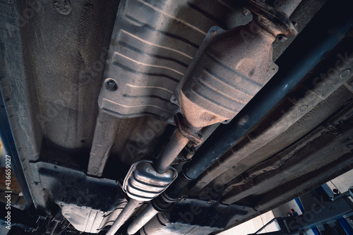 Vehicle underbody exhaust pipe, catalyst, resonator, exhaust system. Old parts require repair and replacement. Car service and maintenance. cardan and outboard bearing