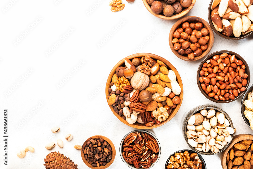 Nuts in bowls set. Cashews, hazelnuts, walnuts, pistachios etc. Healthy food snack mix on white table, top view Nuts in bowls set. Cashews, hazelnuts, walnuts, pistachios etc. Healthy food snack mix on white table, top view