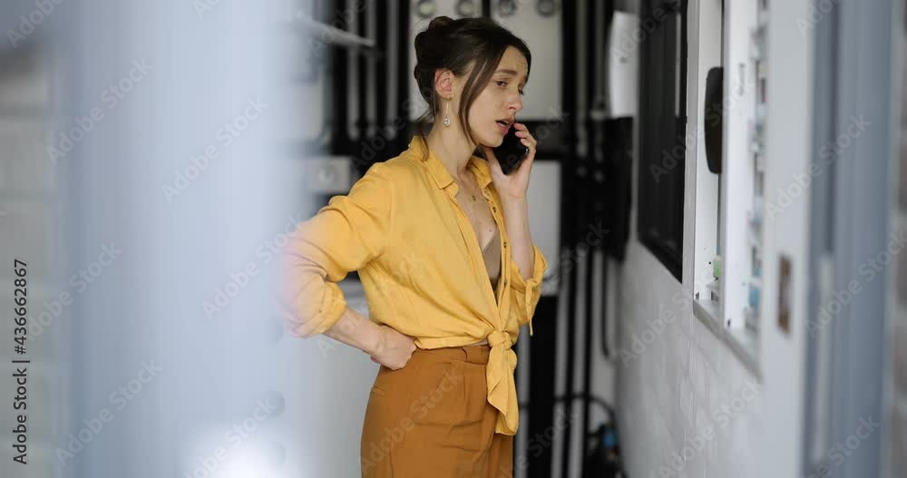Confused woman having problems with electricity at home, speaks on the phone trying to solve the problem. Concept of female incompetence in home electricity Confused woman having problems with electricity at home, speaks on the phone trying to solve the problem. Concept of female incompetence in home electricity