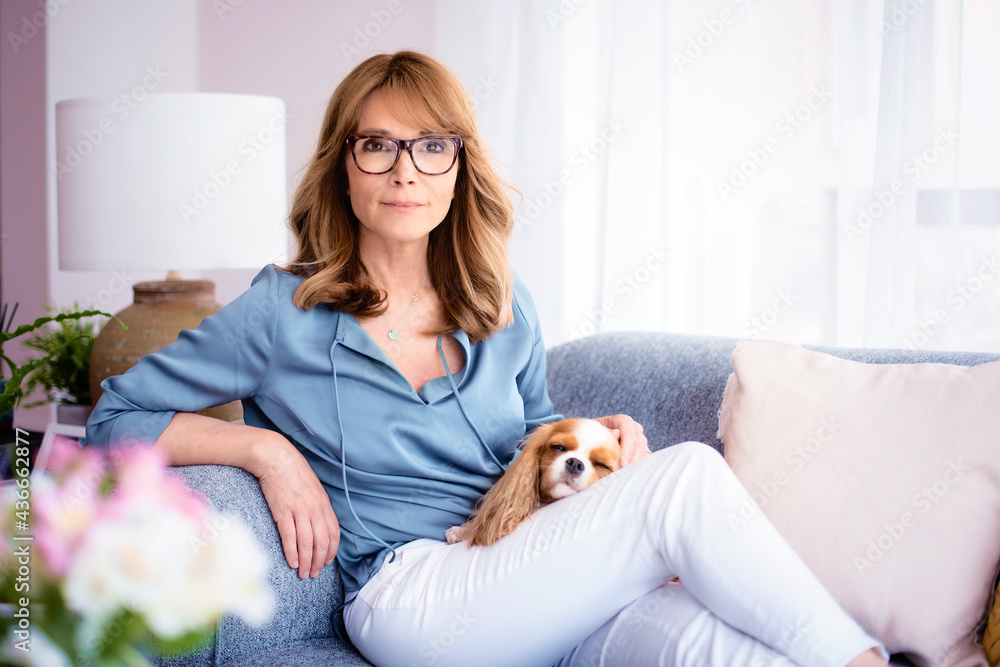 Happy woman sitting on the sofa with her small dog Happy woman sitting on the sofa with her small dog