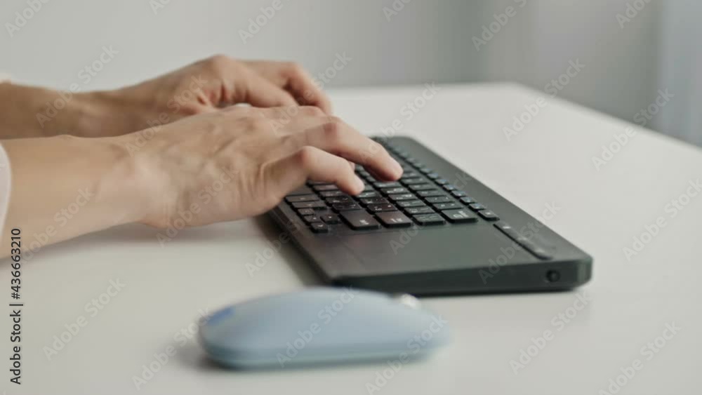 Female hands typing on keyboard and holding computer mouse on light background Female hands typing on keyboard and holding computer mouse on light background
