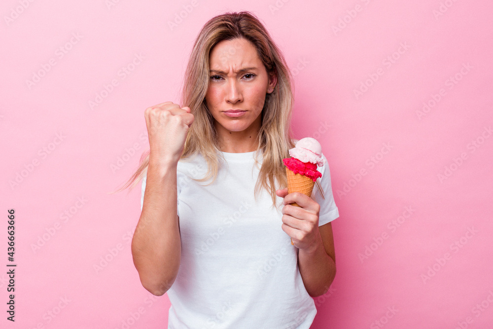 Young australian woman holding an ice cream isolated on pink background showing fist to camera, aggressive facial expression. Young australian woman holding an ice cream isolated on pink background showing fist to camera, aggressive facial expression.