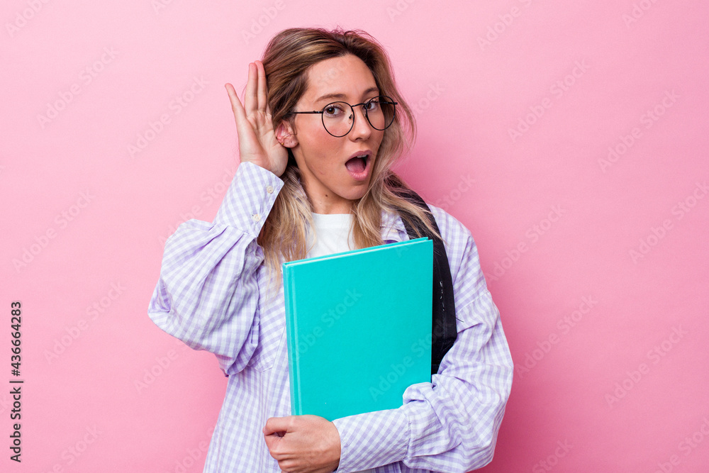 Young student australian woman isolated on pink background trying to listening a gossip. Young student australian woman isolated on pink background trying to listening a gossip.