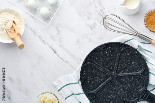 Empty frying pan black, skillet with stone nonstick coating for baking pancakes in shape of breakfast hearts and ingredients on gray concrete table background. Breakfast for Valentines Day. Top view.