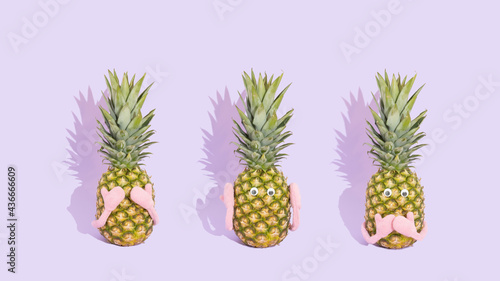 Three fresh pineapples like three wise monkeys. Concept of see no evil, hear no evil and speak no evil. Summer fruit on pastel purple background.