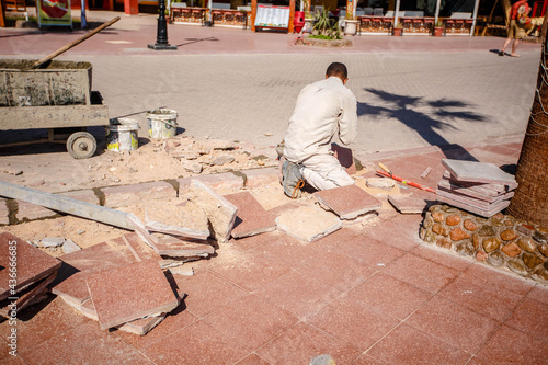 Builder tamping down a new paving brick with a mallet with motion blure effect. photo